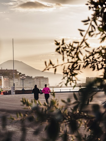 Two runners jogging side by side on a scenic marathon route along a city waterfront at sunrise.