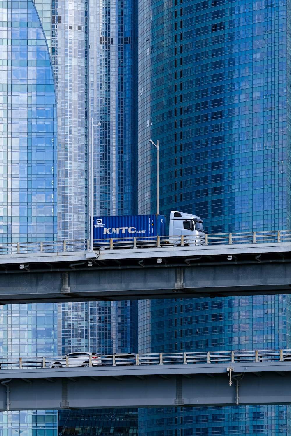 a truck driving over a bridge in front of tall buildings