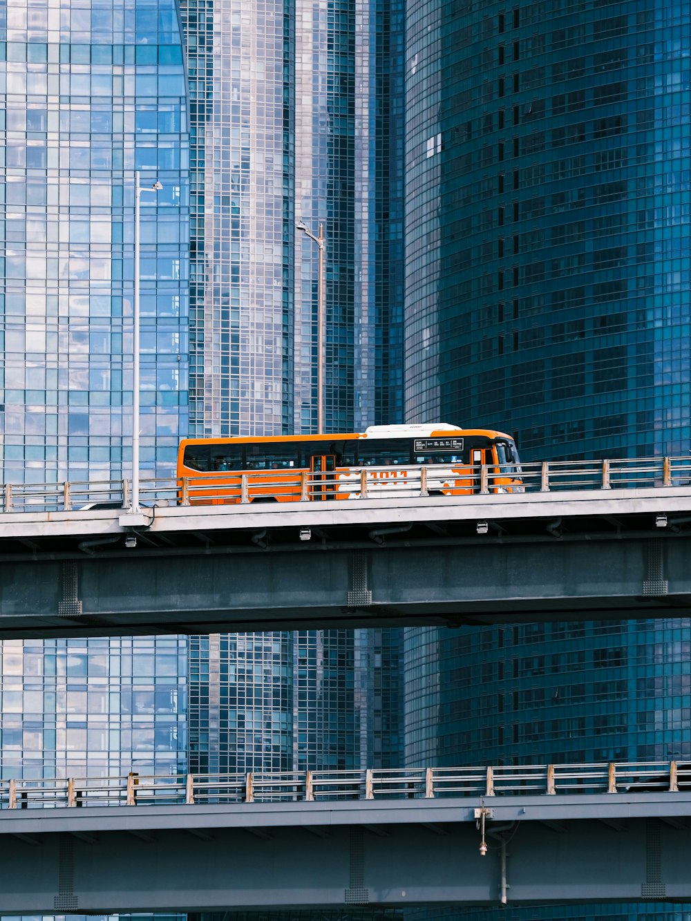 a bus driving across a bridge in front of tall buildings