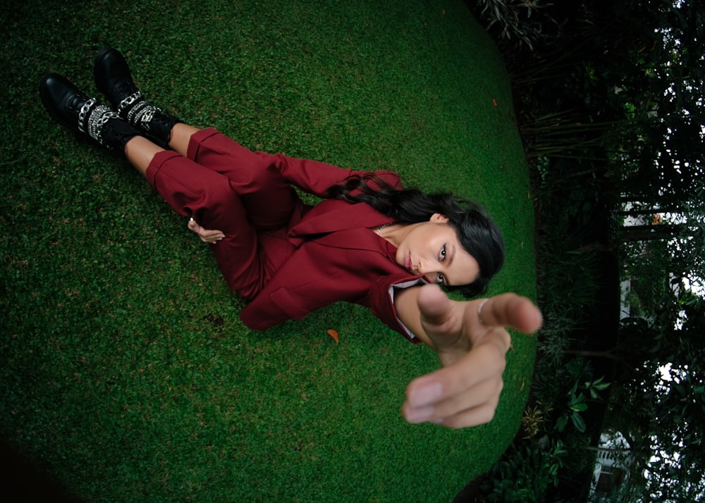 a woman in a red suit laying on the grass