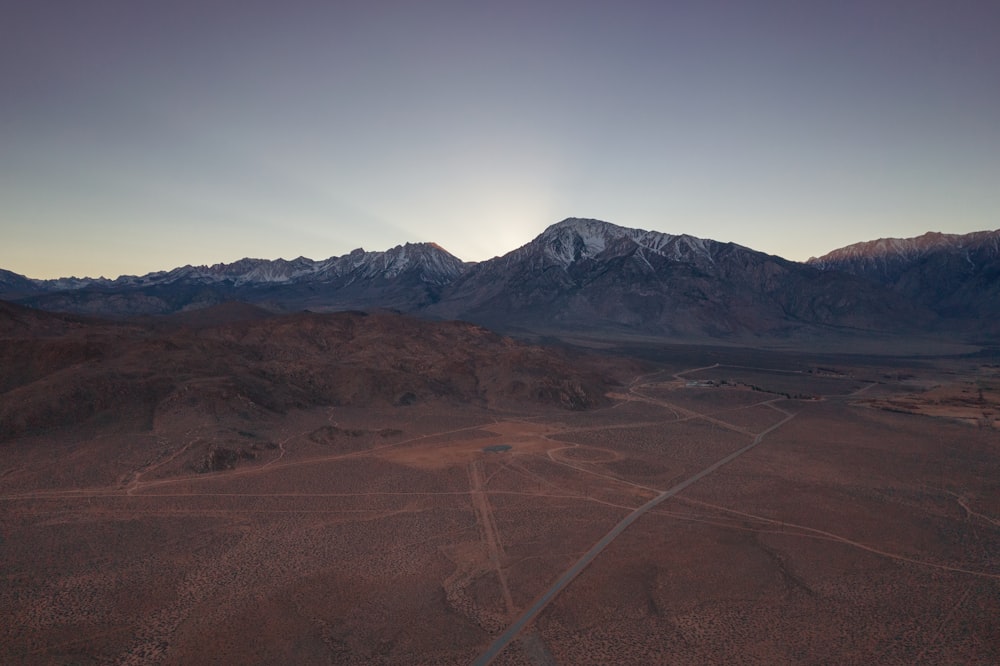 an aerial view of a desert with mountains in the background