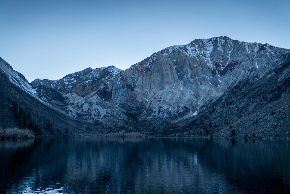 a mountain range is reflected in the still water of a lake