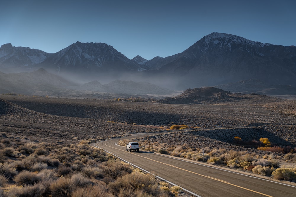 a car driving down a road with mountains in the background