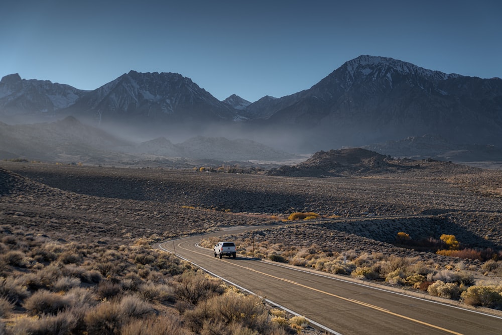Une voiture roulant sur une route avec des montagnes en arrière-plan