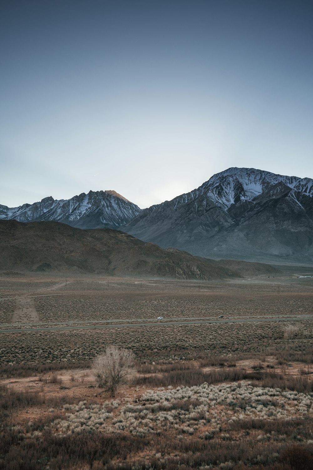 the mountains are covered in snow and brown grass