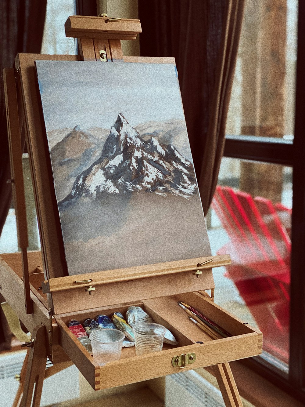 an easel with a painting of a mountain