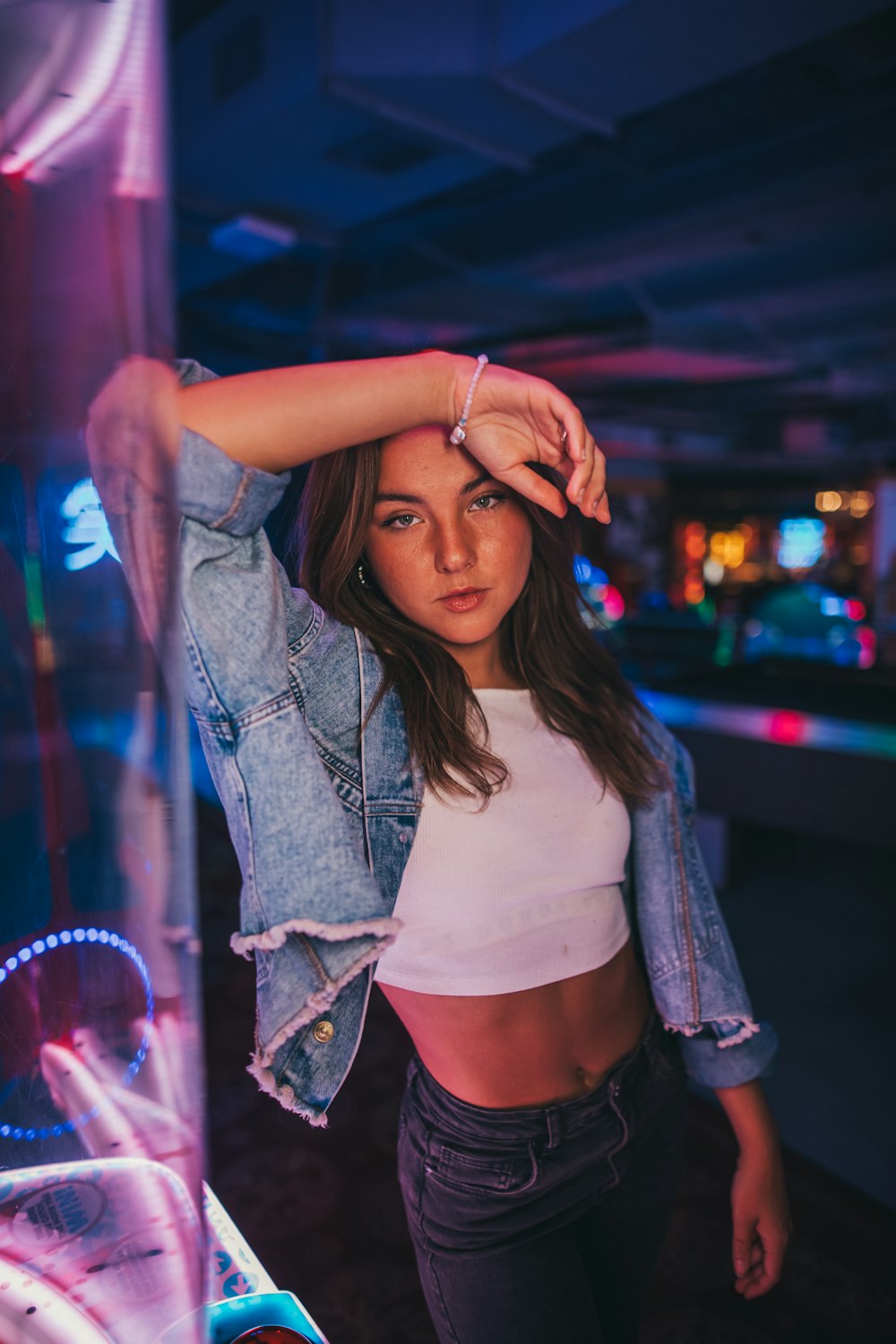 a beautiful young woman standing next to a neon sign