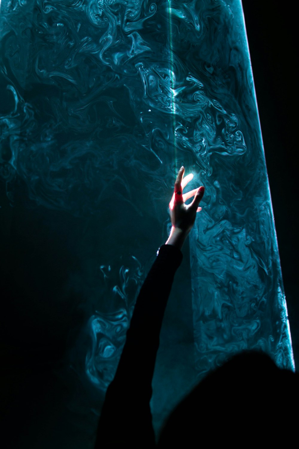 a person reaching up to a wall with a light shining on it