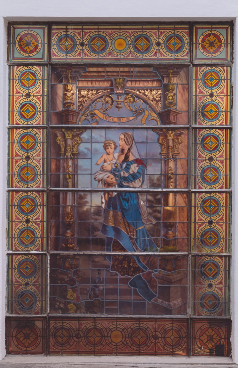 a stained glass window with a woman holding a child