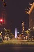 a city street at night with a tall obelisk in the background