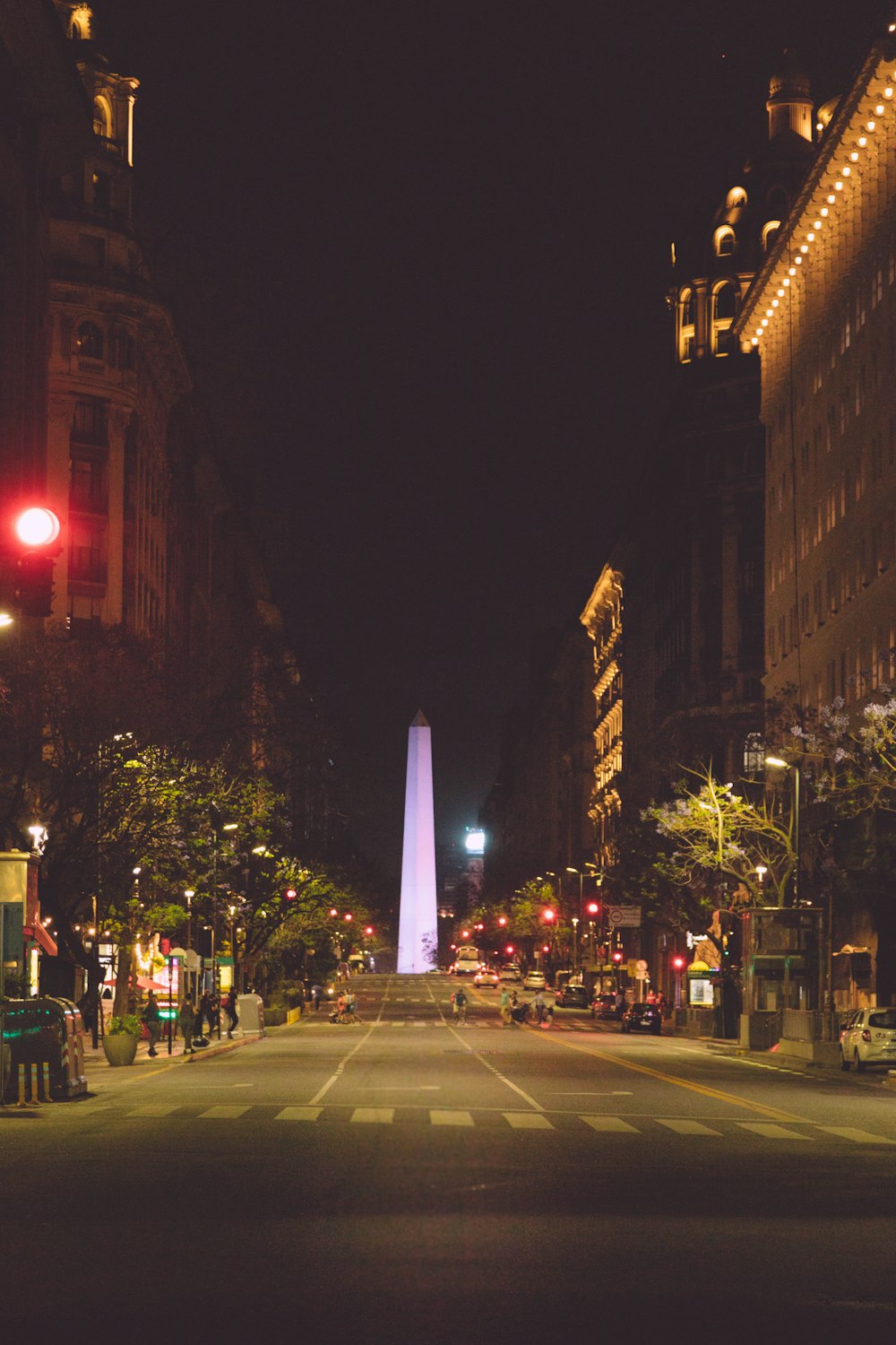 a city street at night with a tall obelisk in the background