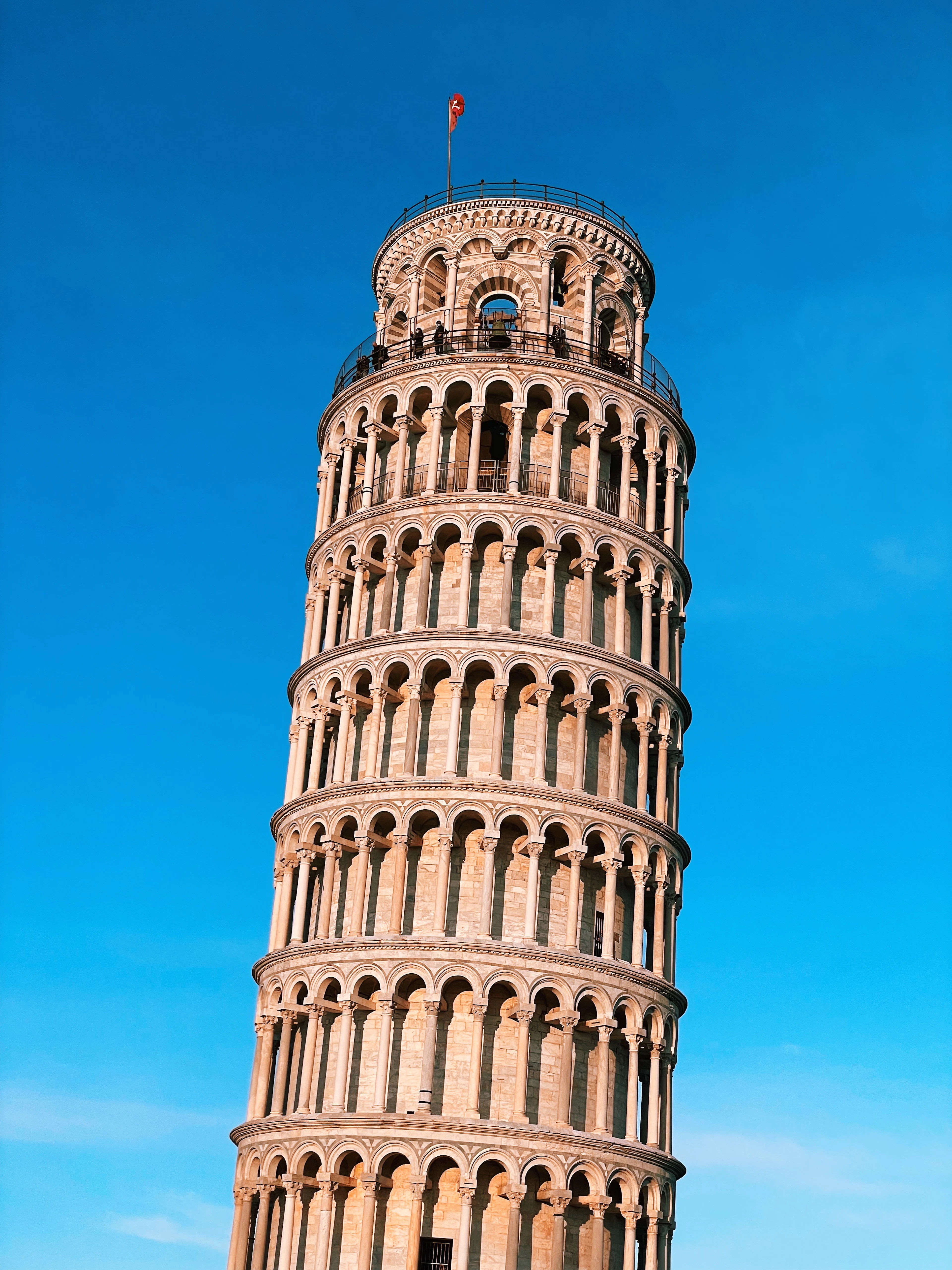 The Leaning Tower of Pisa seen from a low angle against a clear blue sky.