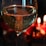A close-up of a wine glass filled with sparkling wine, capturing the bubbles as they rise to the surface. In the background, two softly glowing candles provide a warm, intimate ambiance.