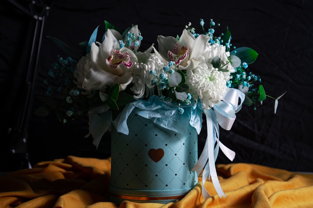 a blue vase with white flowers on a yellow blanket