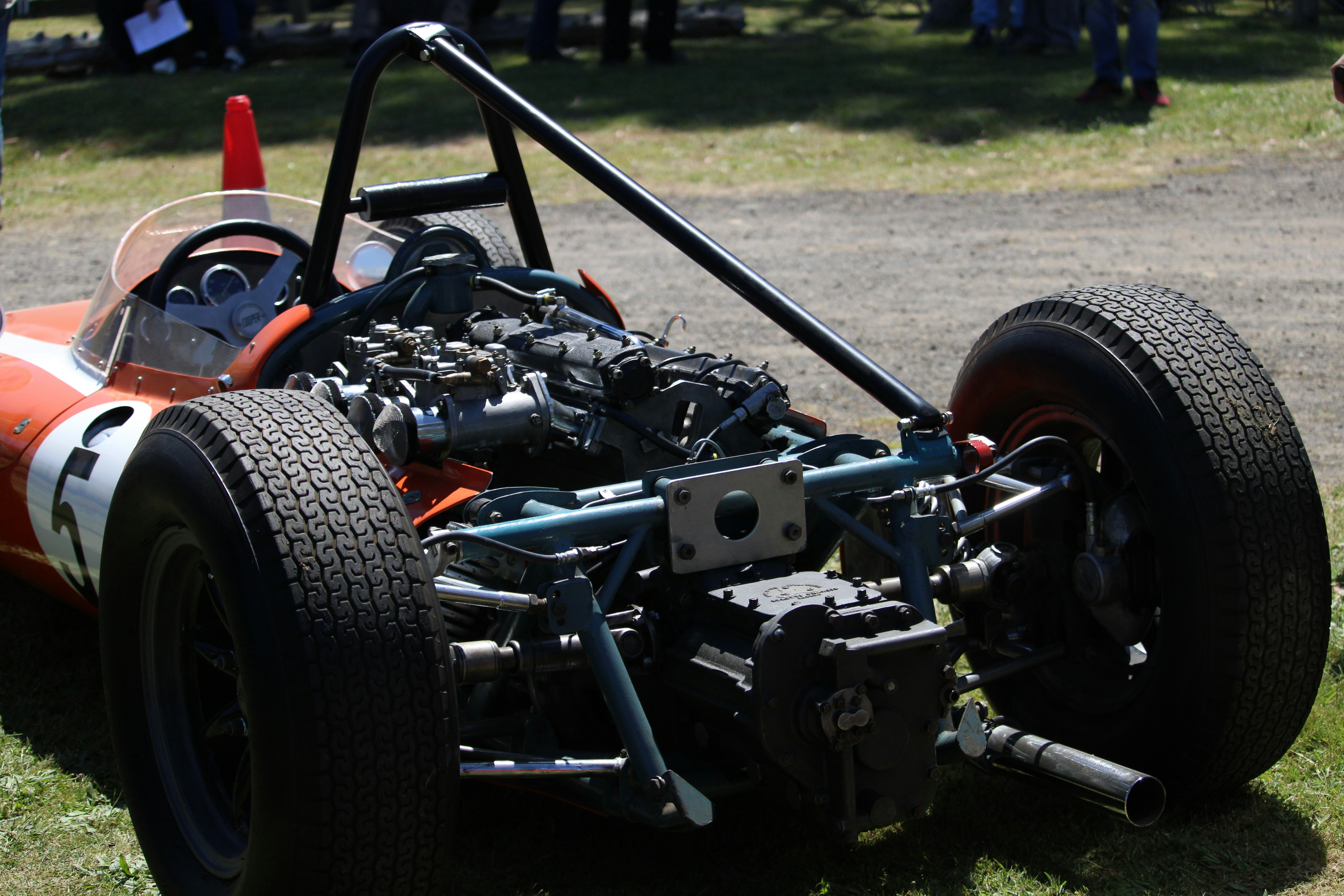 an orange race car sitting on top of a lush green field