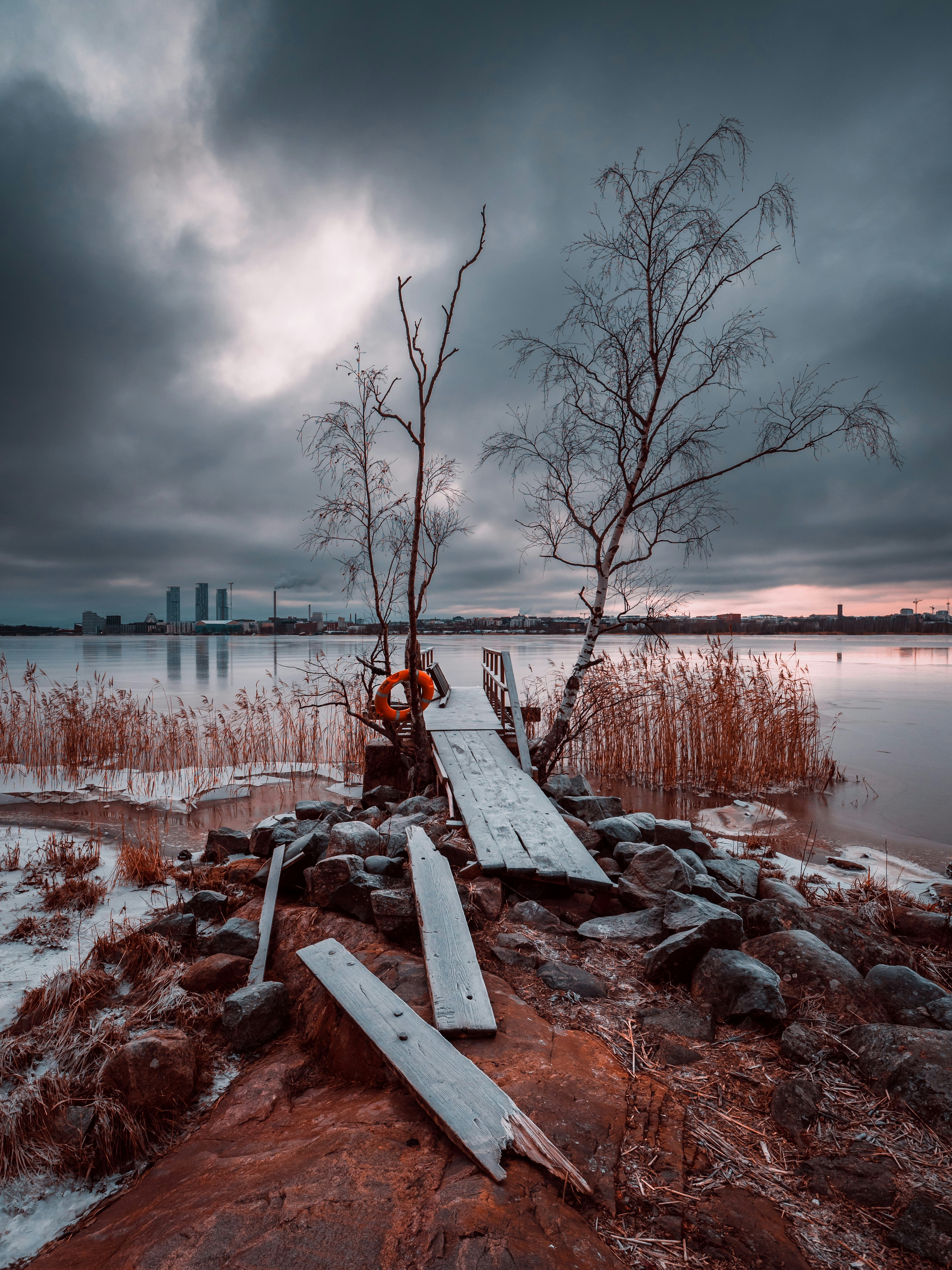 a wooden dock sitting next to a body of water under a cloudy sky
