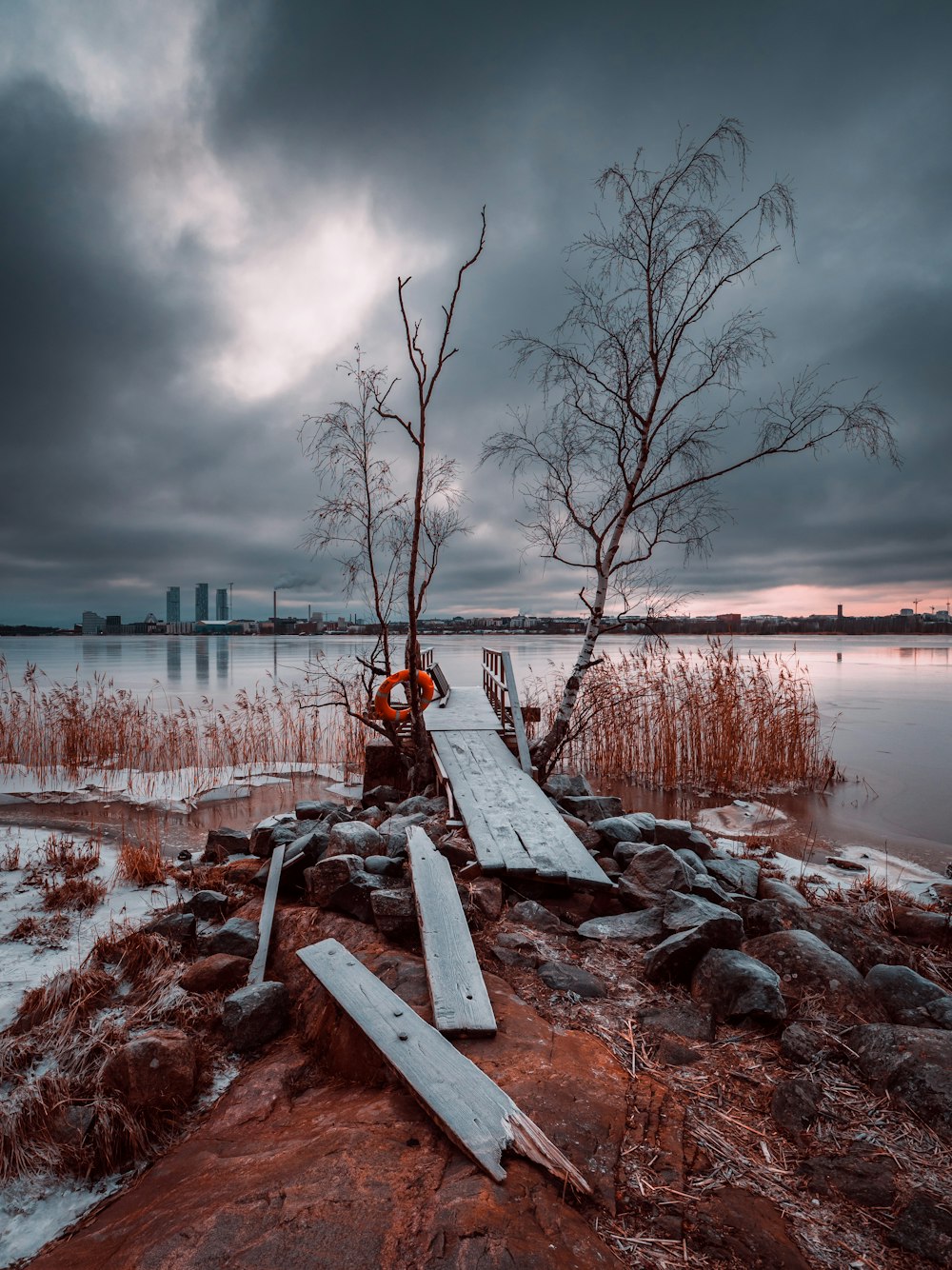 a wooden dock sitting next to a body of water under a cloudy sky