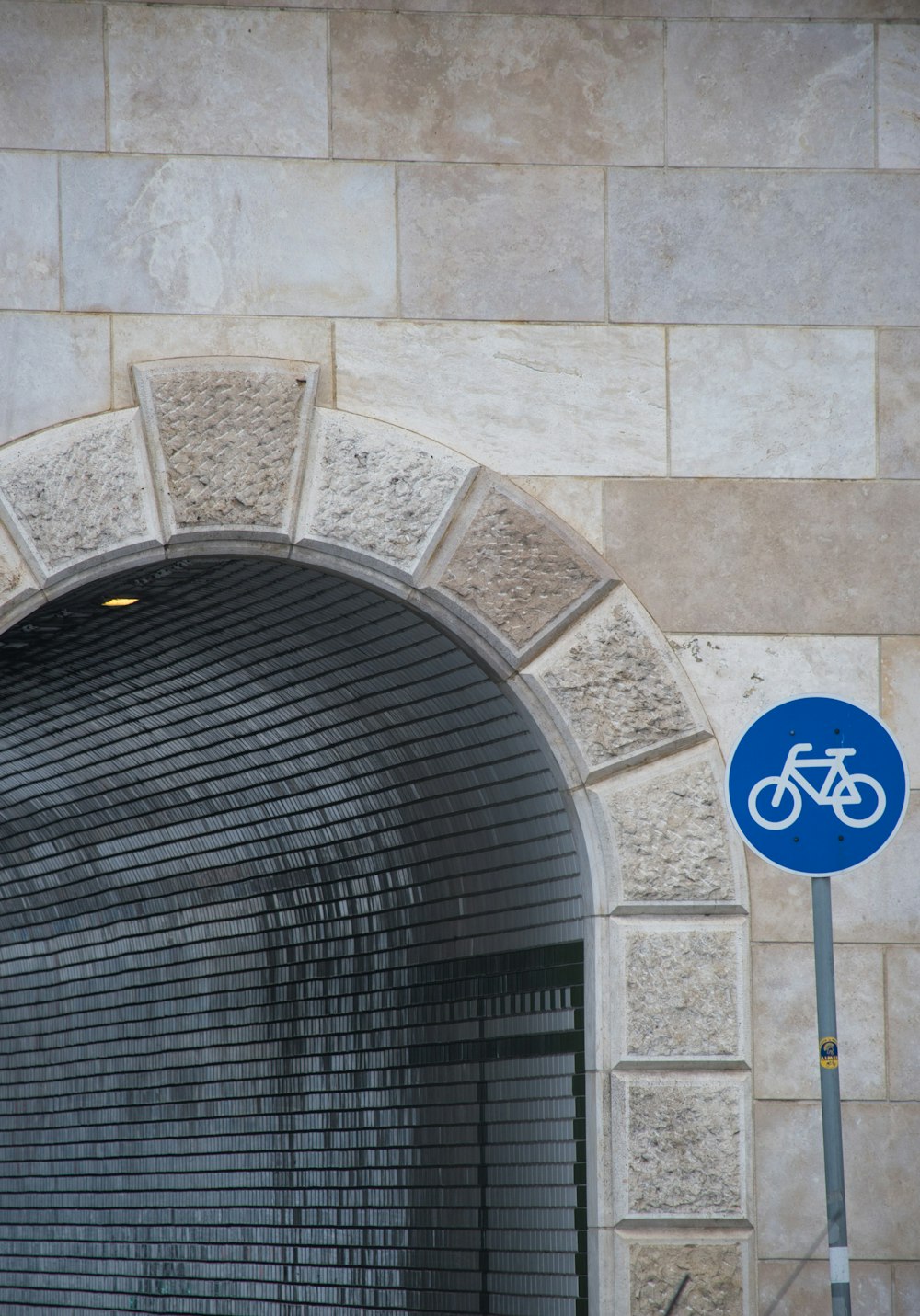 Un letrero de bicicleta frente a un arco de piedra