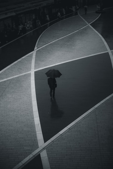 A still from a moody black-and-white short film showing a lone figure walking through a rainy Toronto street.