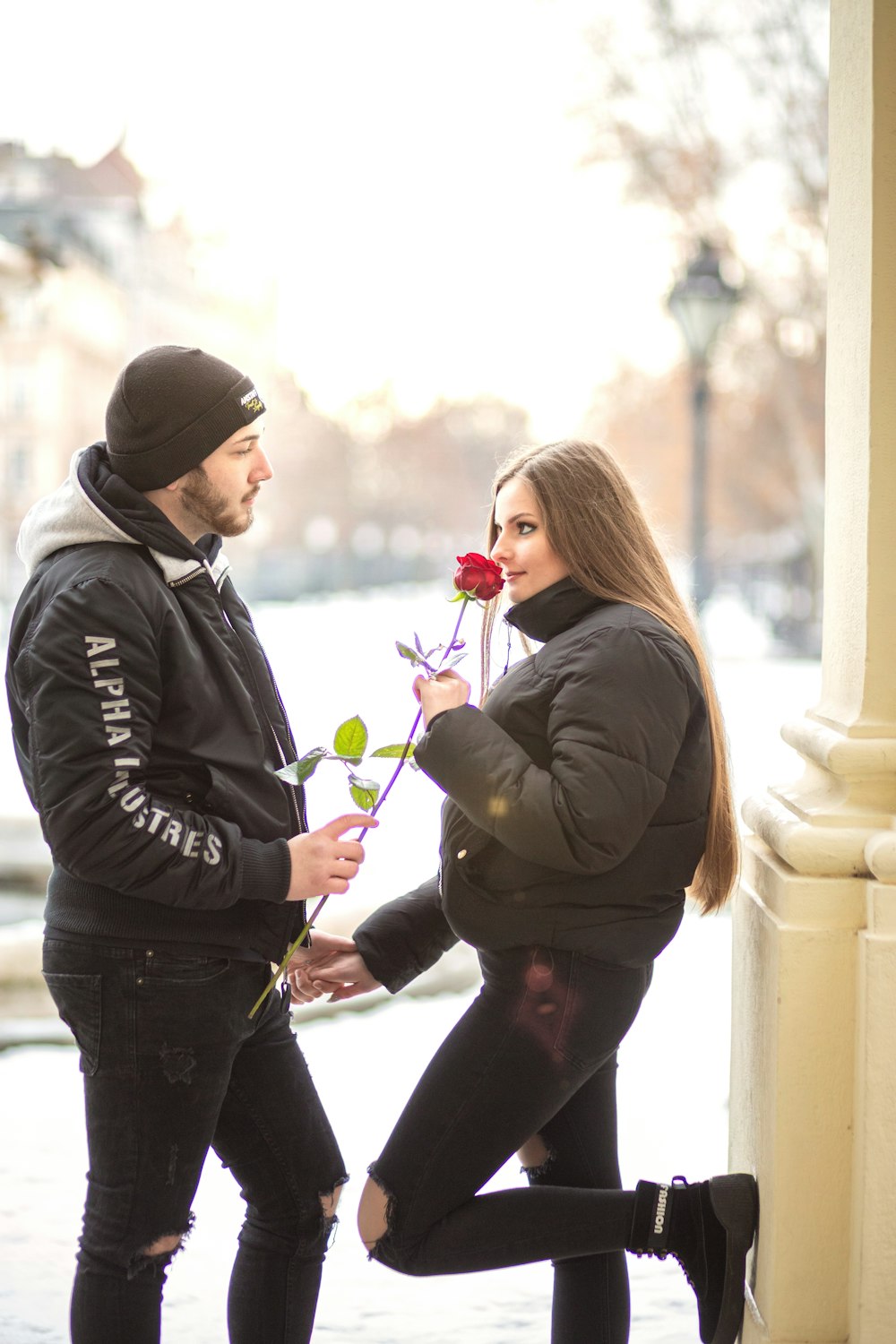 a man kneeling down next to a woman holding a rose