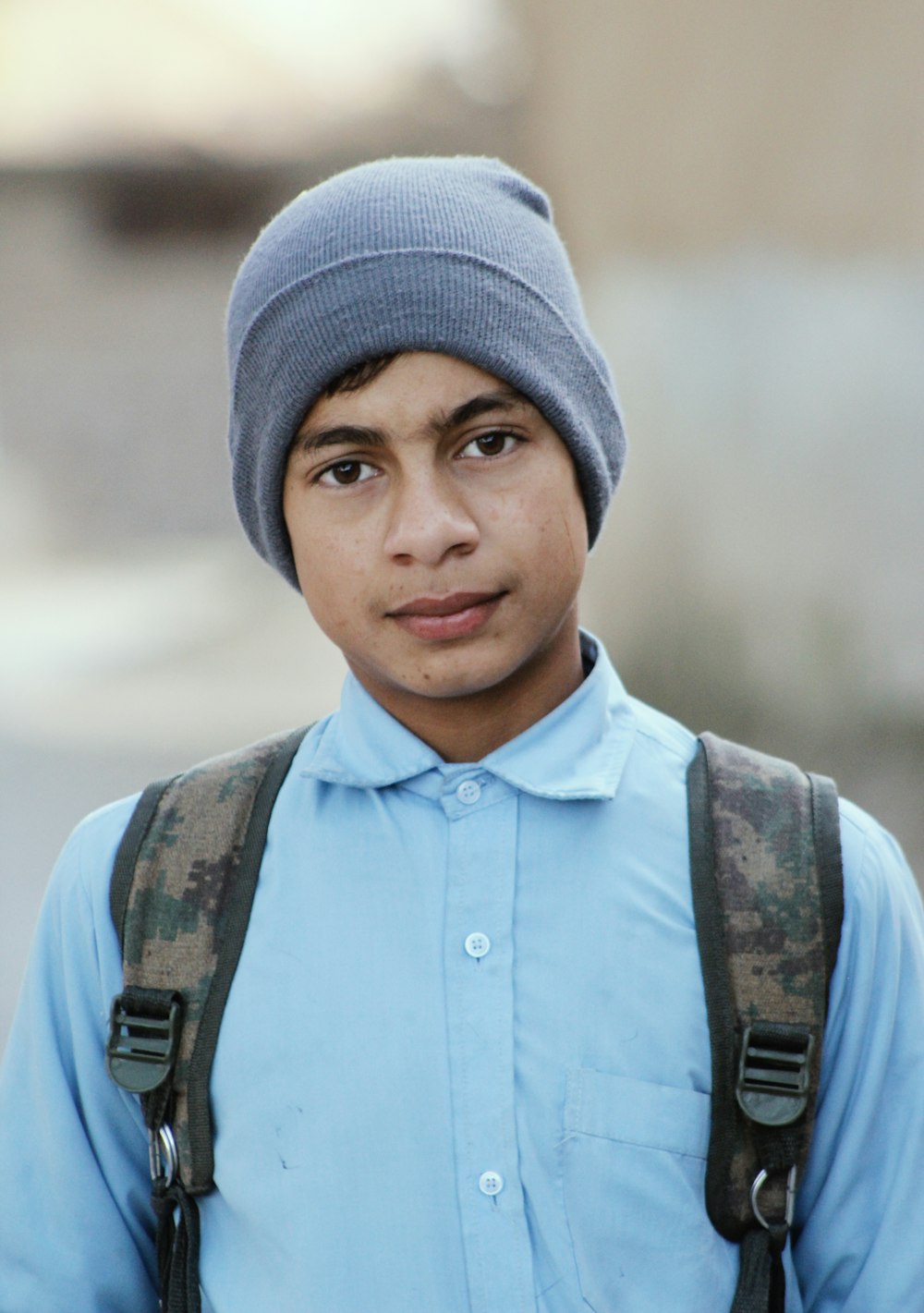 a young man wearing a blue shirt and a gray hat