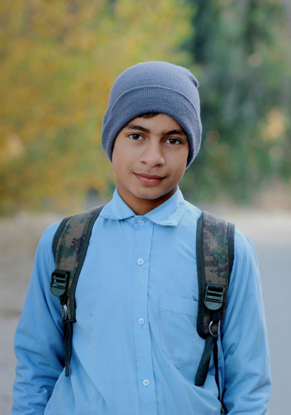 a young man wearing a blue shirt and a gray hat