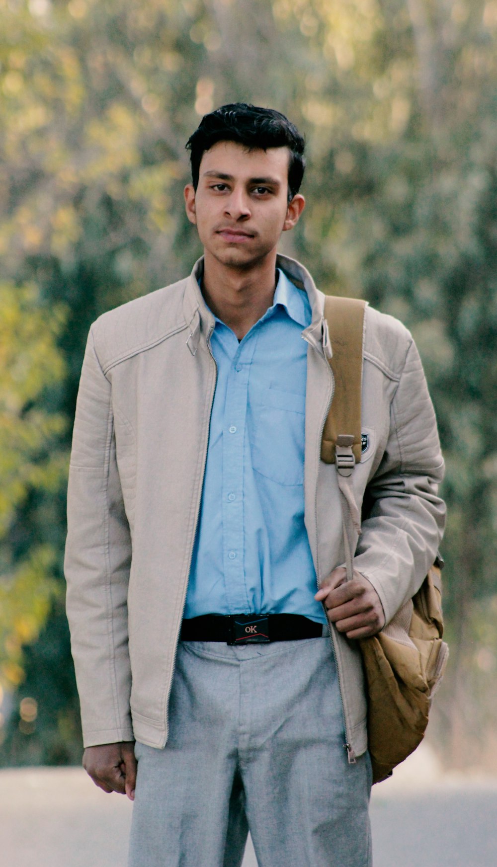 a man in a blue shirt and tan jacket