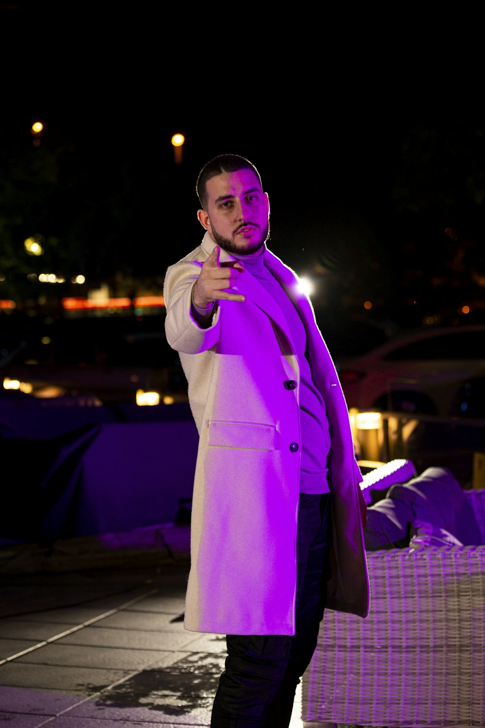 a man in a purple coat pointing at the camera
