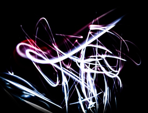 A series of dynamic, neon light trails in white and pink against a dark background, creating an abstract and energetic pattern.