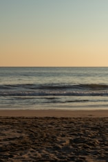 a person walking on the beach with a surfboard