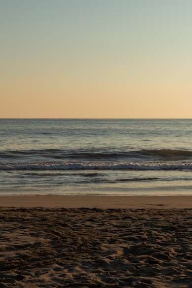 a person walking on the beach with a surfboard