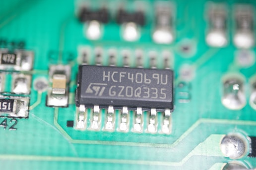 A close-up view of a green printed circuit board featuring an integrated circuit chip marked with the text 'HCF4069U GZ0Q335'. The board also contains various small electronic components such as resistors and capacitors, and conductive traces that form connections between components.