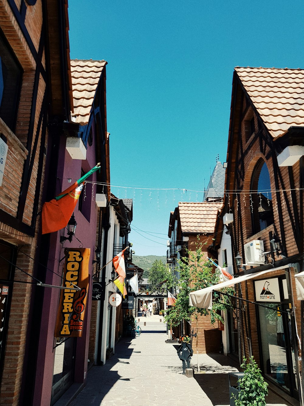 a narrow street lined with wooden buildings and flags