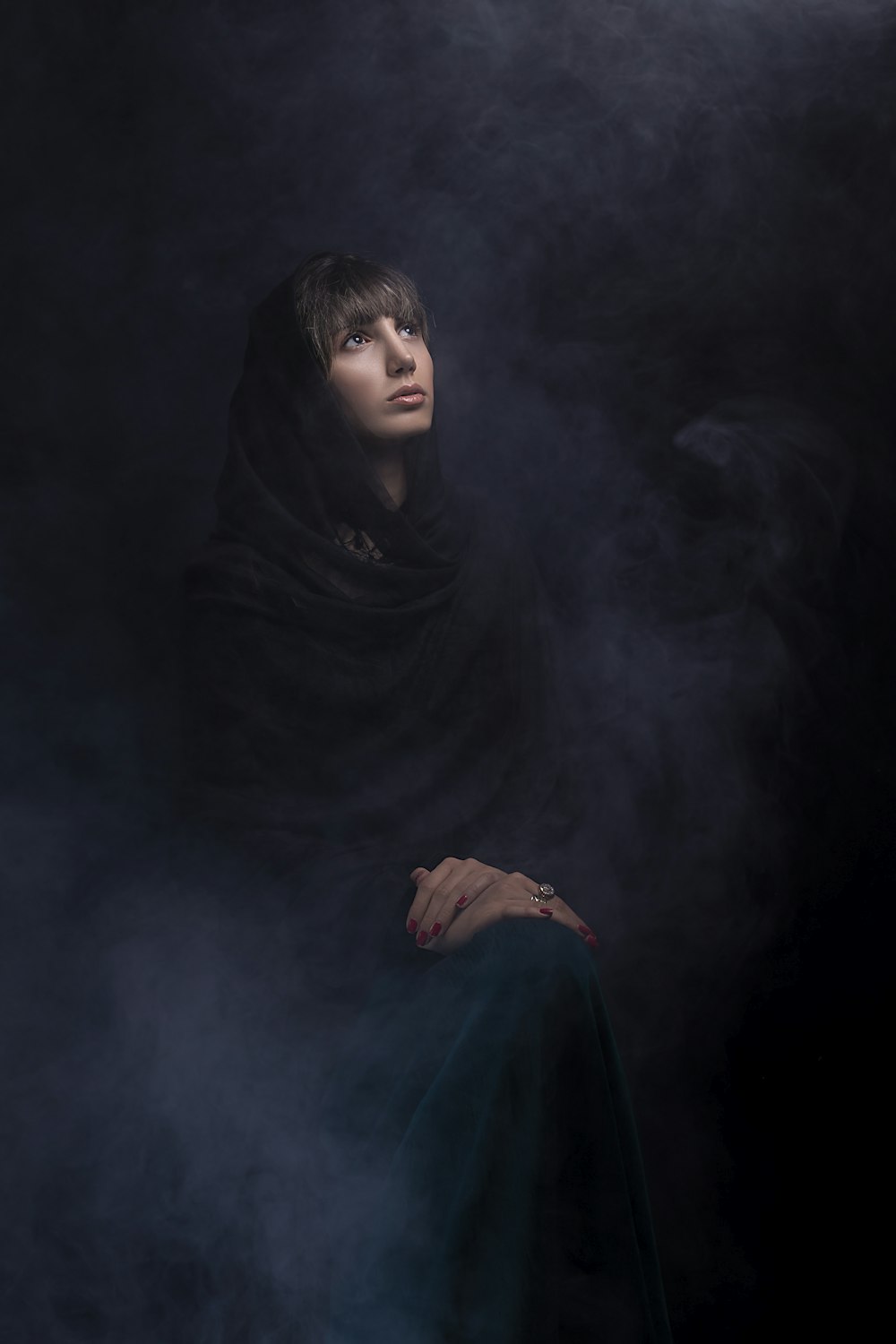 a woman in a black shawl sitting in smoke