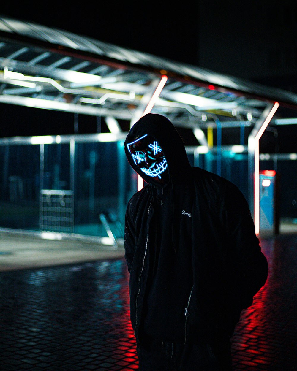 a man in a black hoodie wearing a neon mask