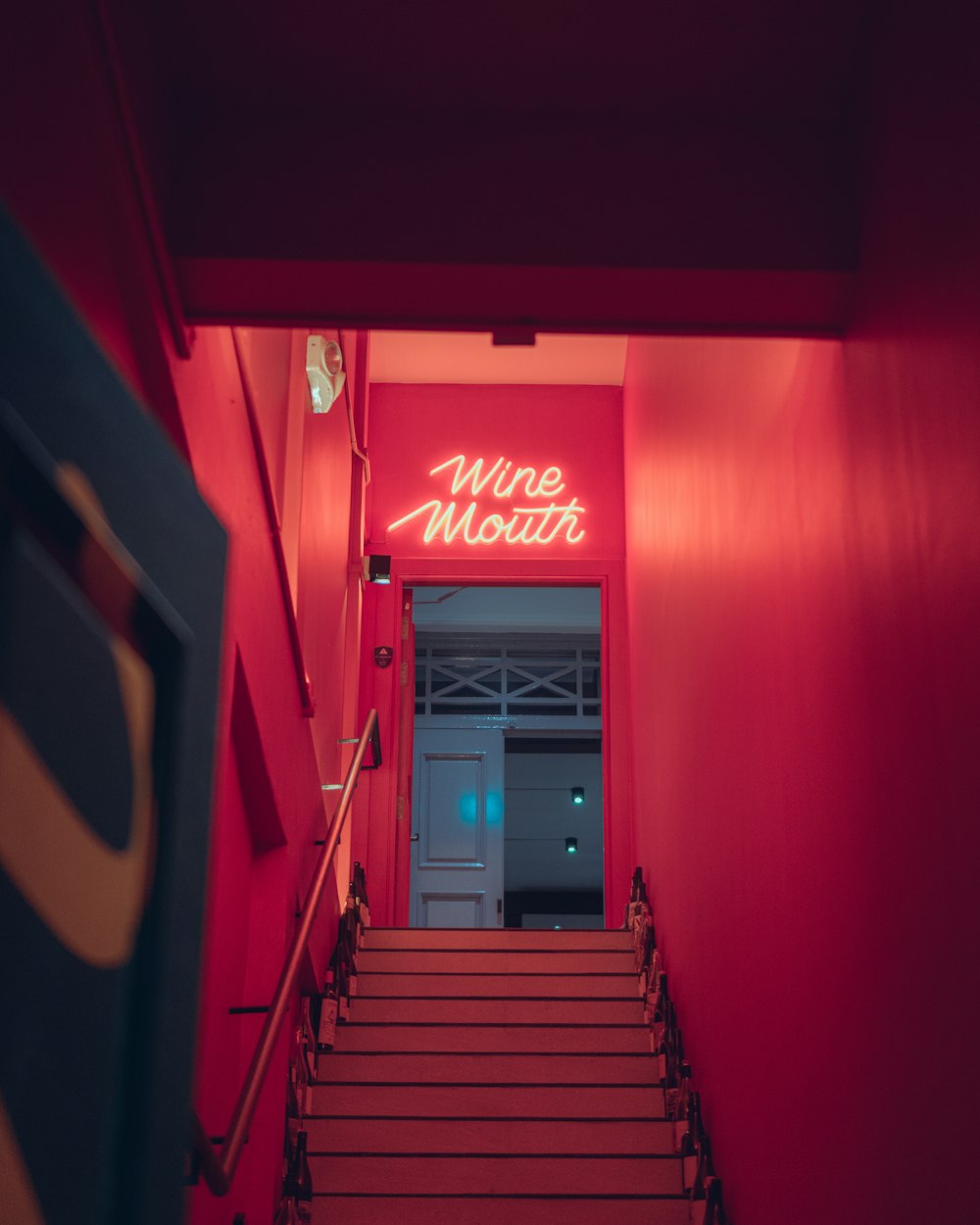 a red staircase with a neon sign above it