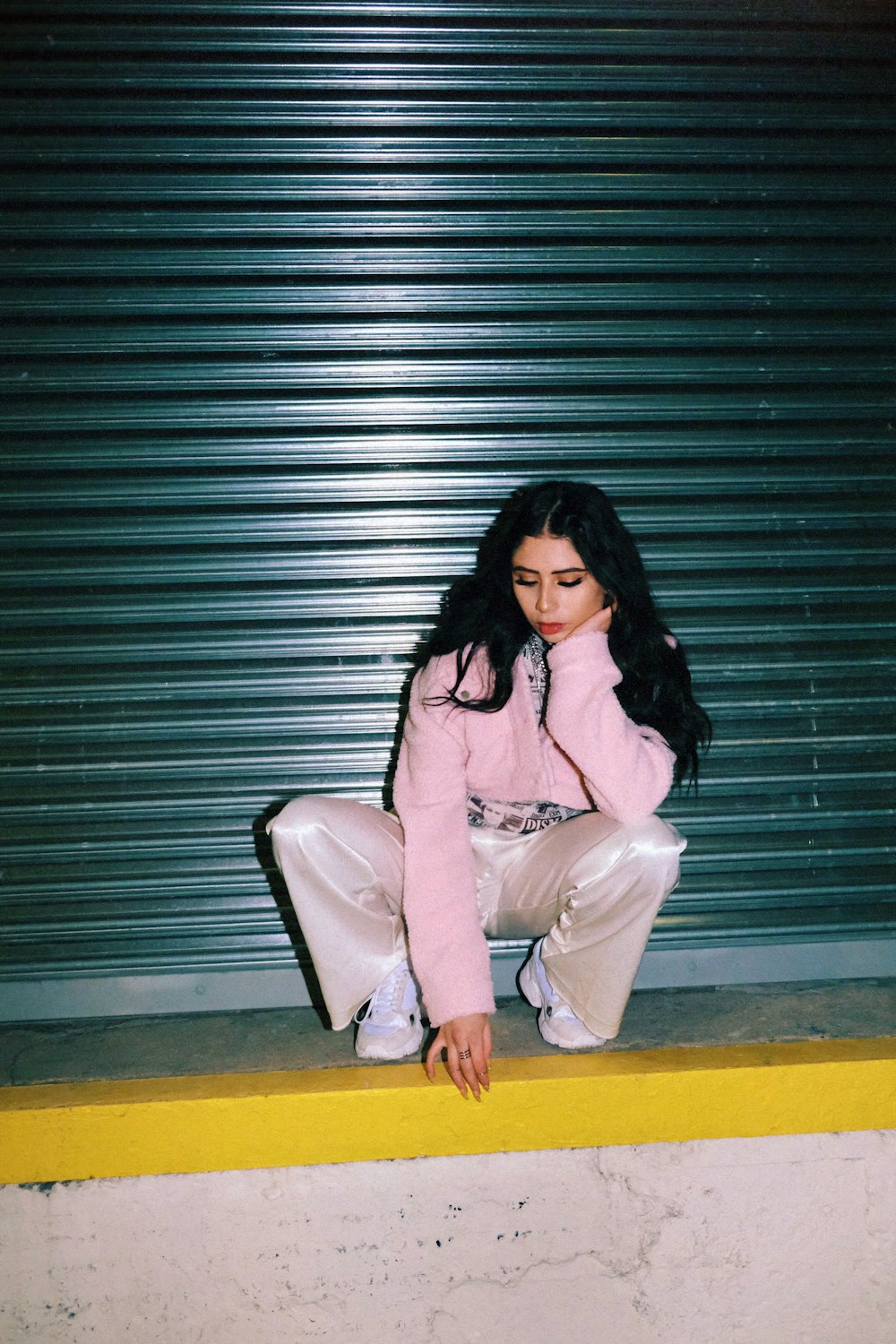 a woman in a pink jacket is sitting on a ledge