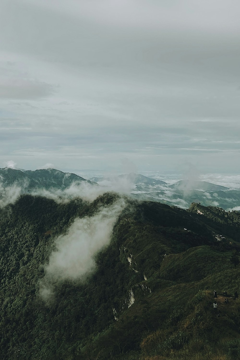 a view of the mountains and clouds from the top of a hill