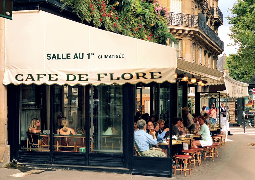 a group of people sitting outside of a cafe