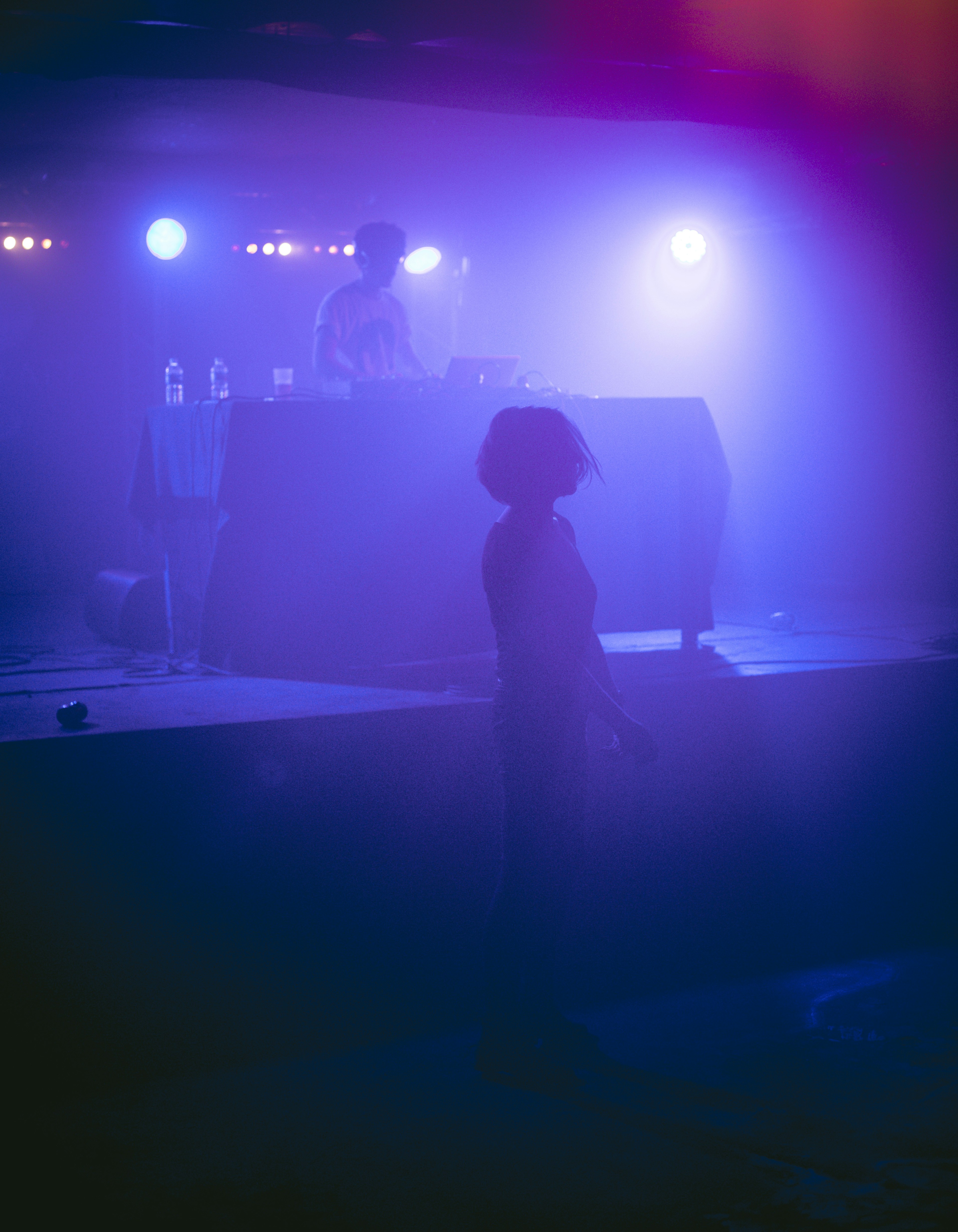 DJ playing music on stage with colorful lights.