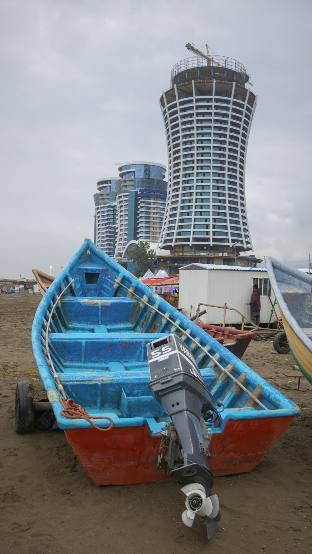 Un barco azul y rojo sentado en la cima de una playa de arena