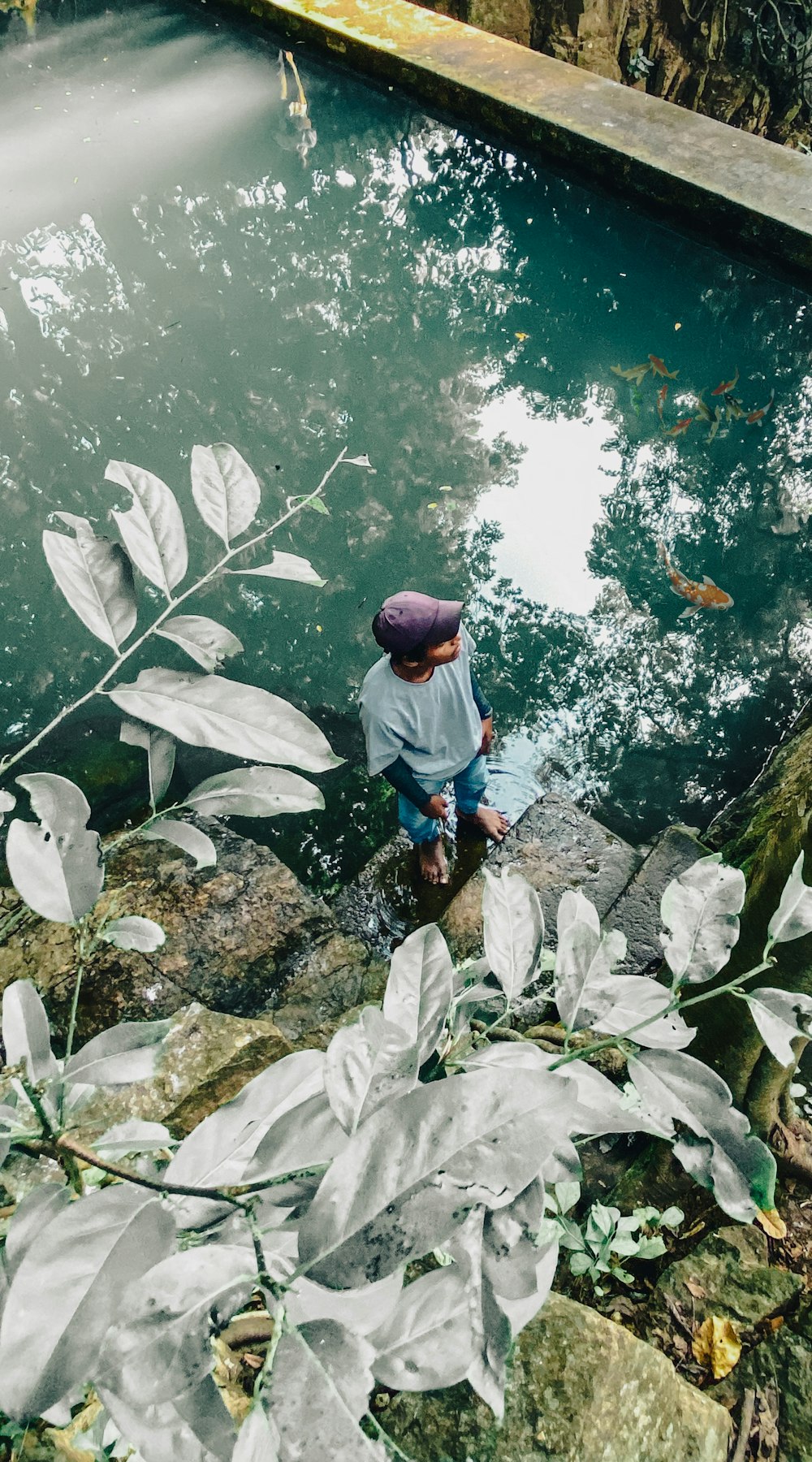 a man sitting on a rock next to a body of water