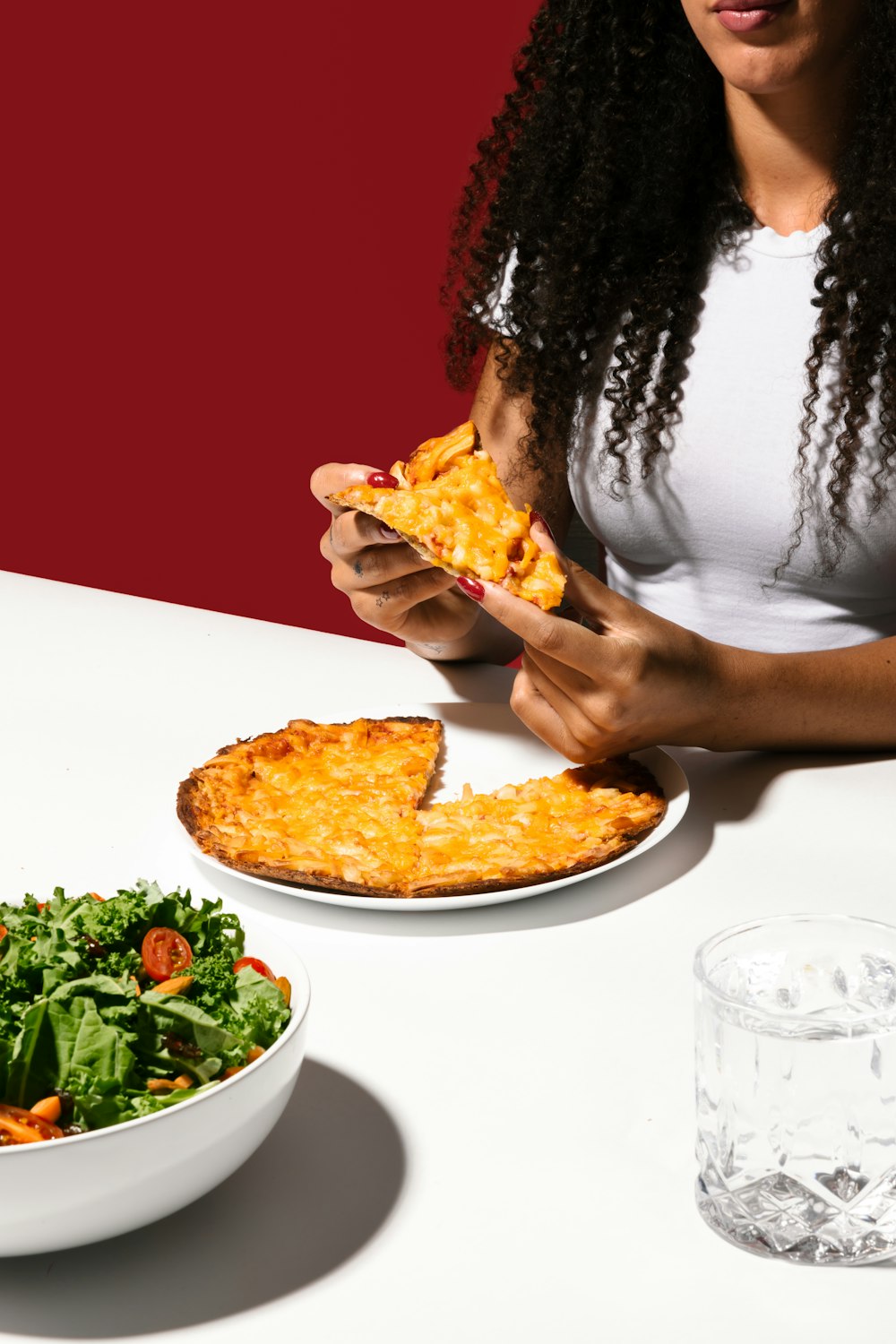 a woman sitting at a table eating a piece of pizza