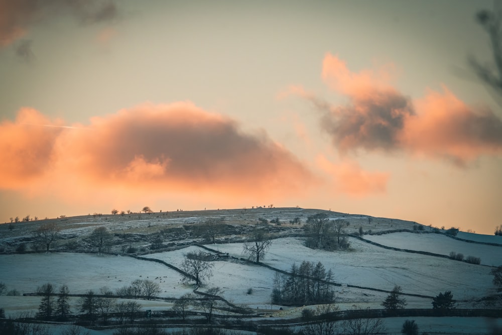 a snow covered hill with a pink sky in the background