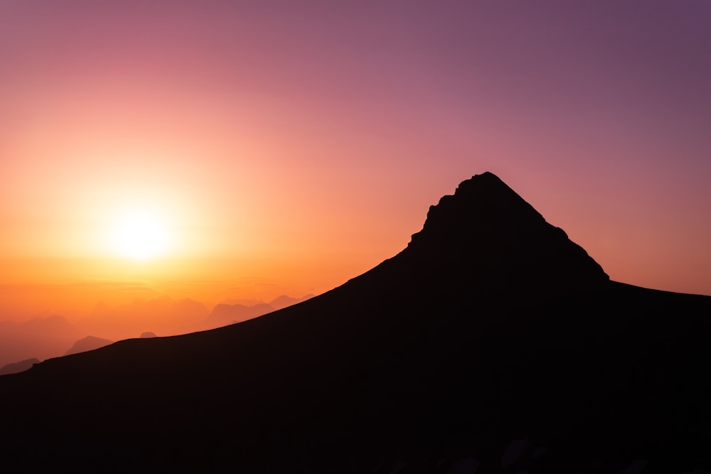 the sun is setting behind a mountain peak