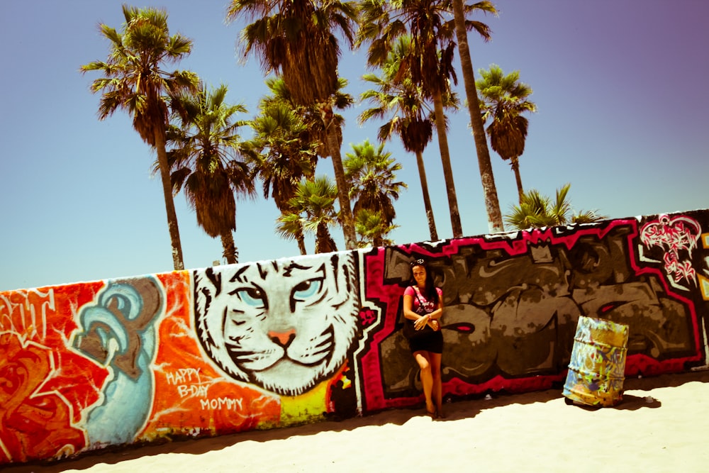 a woman standing next to a wall covered in graffiti