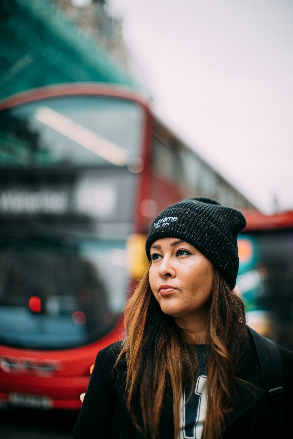 a woman standing in front of a double decker bus