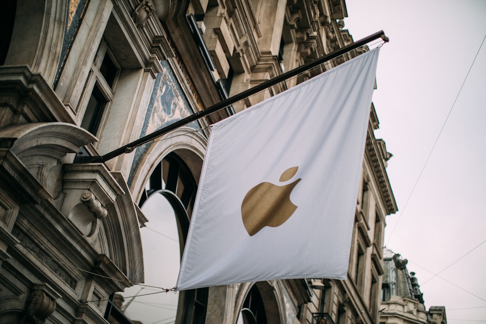 a white and gold apple flag hanging from a building