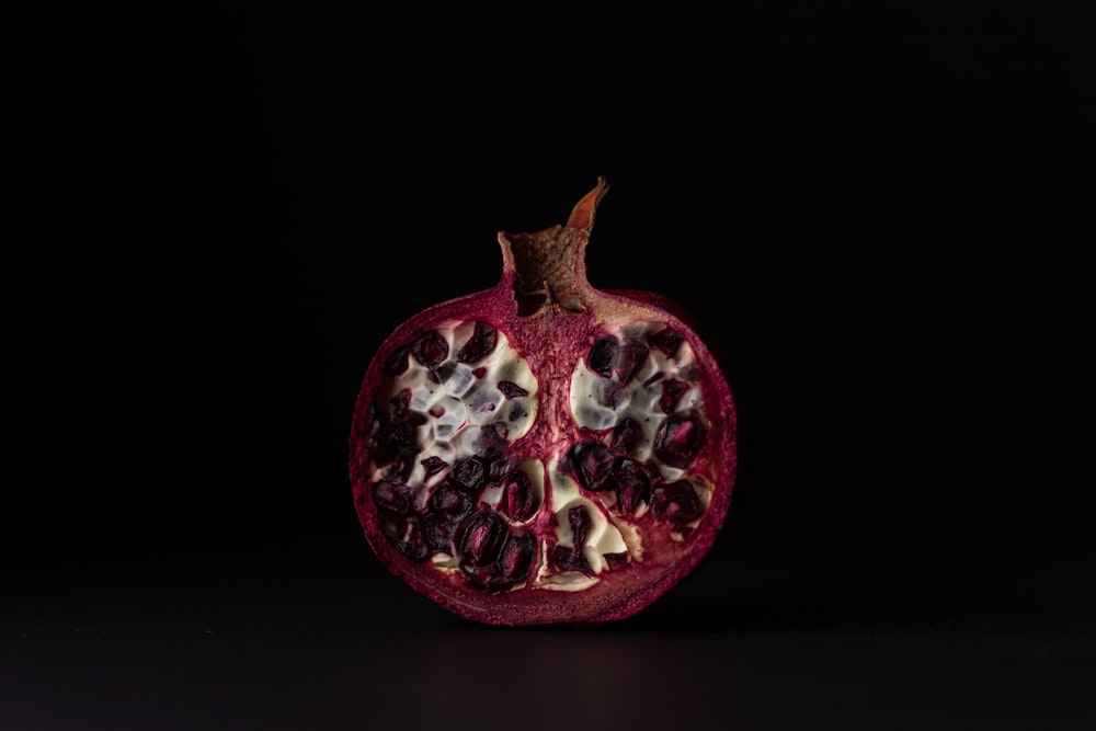 a pomegranate cut in half on a black background