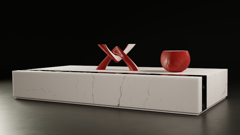 a white box with a red vase on top of it